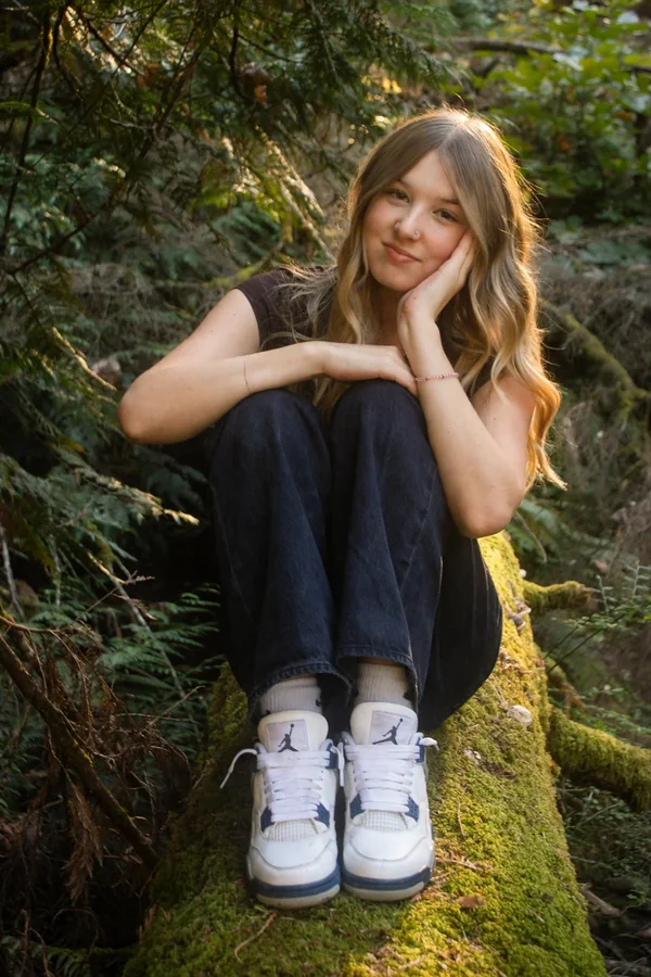 Lynden crouching with her chin resting on her hand outdoors