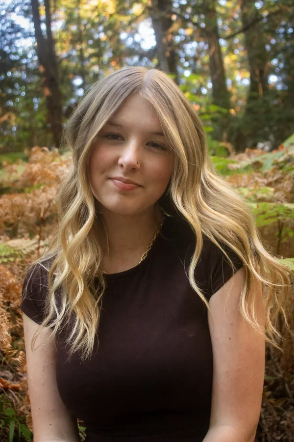 Close-up portrait of Lynden looking directly at the camera in soft forest light