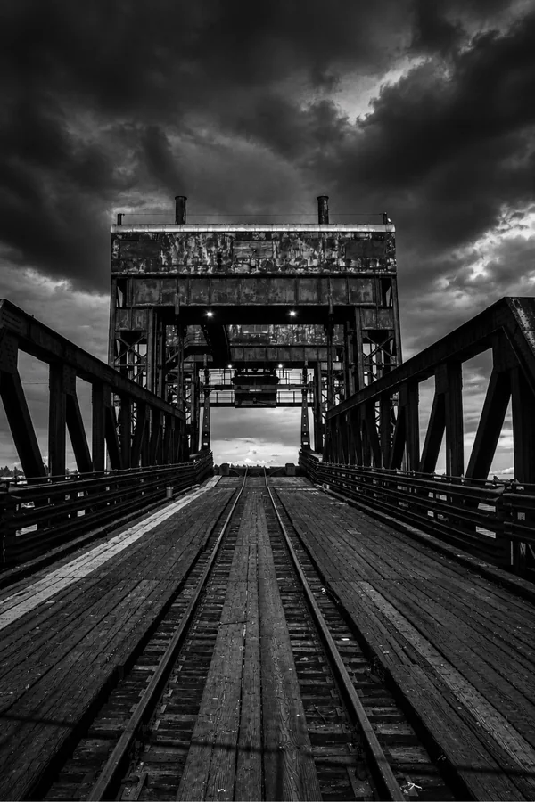 Black-and-white railway bridge beneath dramatic clouds