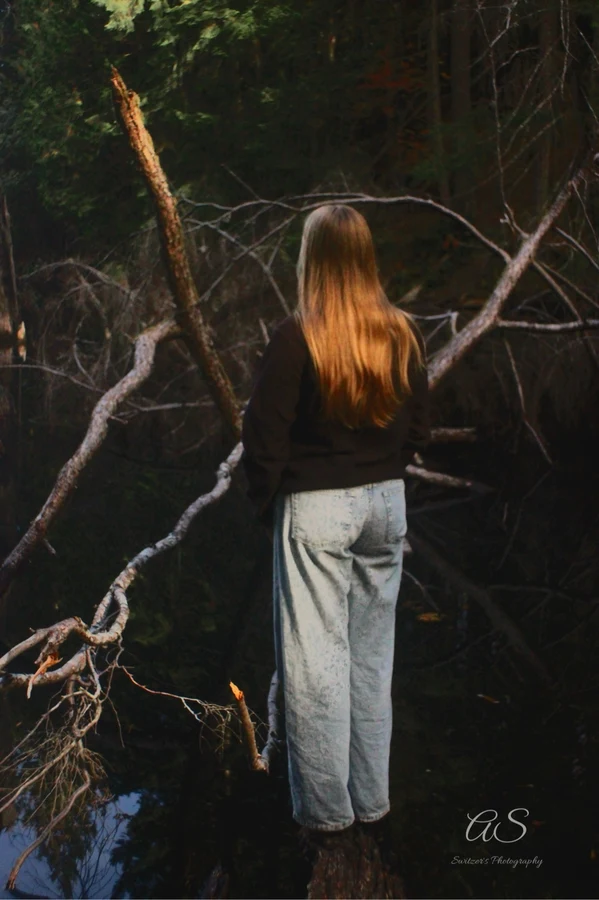 Young woman seen from behind among tangled branches in the woods
